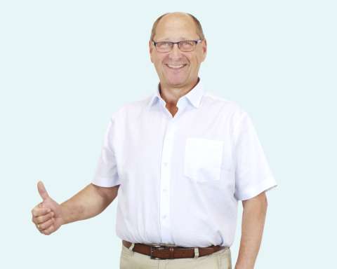 Alois Kammerer lächelt nach seiner Gewichtsabnahme im weißen Hemd und hält den Daumen hoch.